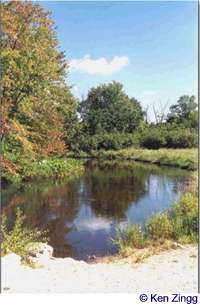 The first touch of fall color frames the glassy surface of the White River along Rustic Road 22
