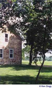 Sun and shadows play on the lawn and over the face of the old stone house